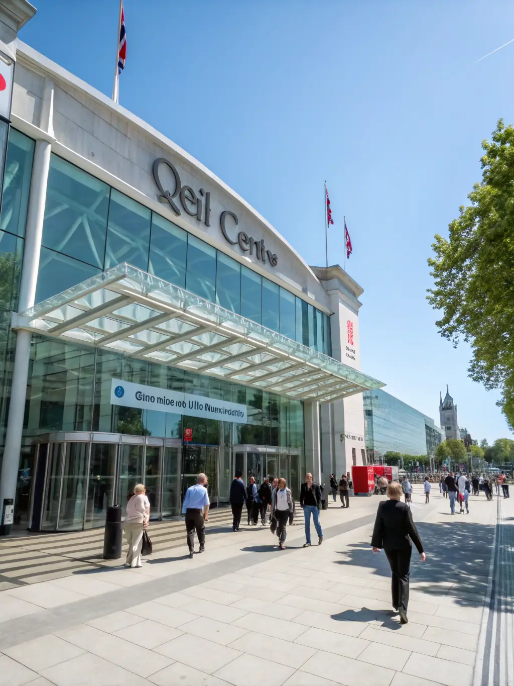 A photograph of the conference venue, the QEII Centre in London, with attendees entering the building on a sunny morning.